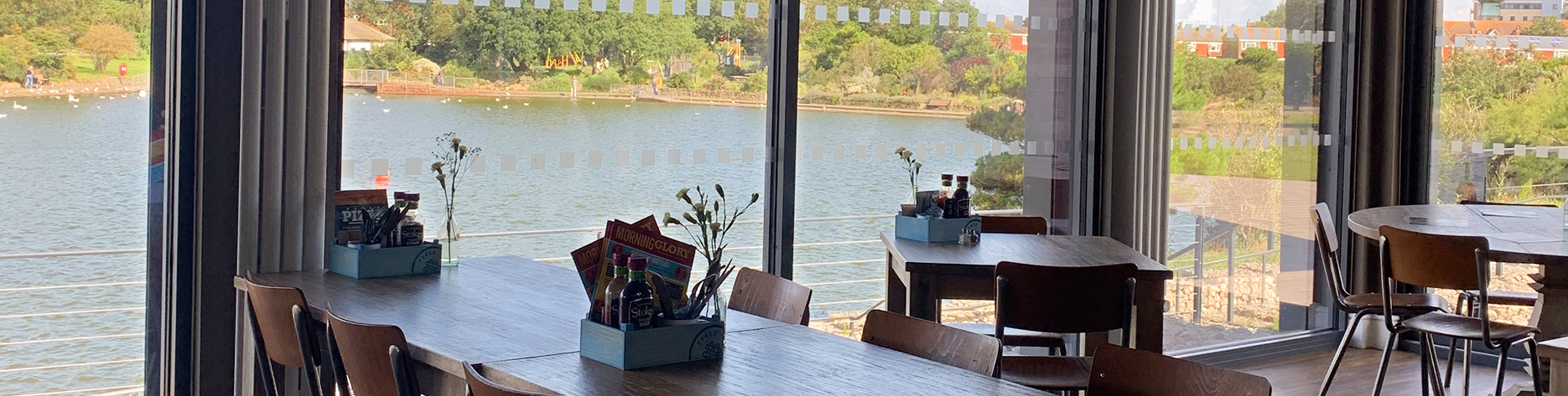 Tables at Princes Perch cafe in Eastbourne looking out onto the sunny lake in Princes Park